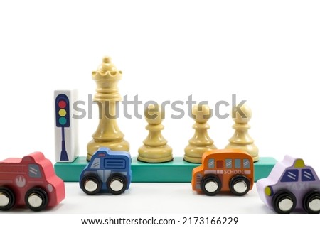 Traffic guards or teachers help children to school across the highway, illustrated by wooden chess pieces and toy cars isolated on a white background