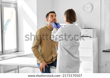 medicine, healthcare and people concept - female doctor checking lymph nodes of man patient at hospital Royalty-Free Stock Photo #2173170507