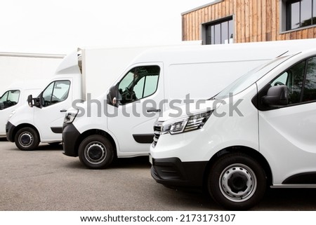 Several cars vans trucks parked in parking lot for rent delivery white vans in service van truck front of entrance of warehouse distribution logistic society Royalty-Free Stock Photo #2173173107