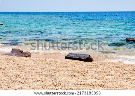Sandy beach with rocks on the shore and water.
