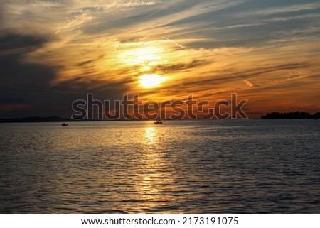 Red orange bright sunset with large sun on the sea. Red sun on the horizon the sea surface at sunset time, with boat