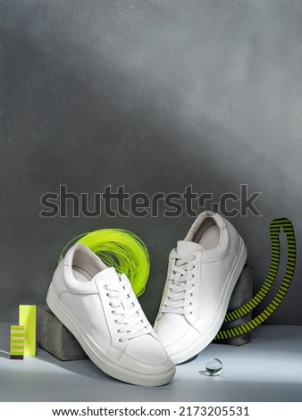 Stylish women's white sneakers on podium. Trendy female accessories. Conceptual still life of footwear. Shoes fashion photography. Minimalist fashion creative concept.