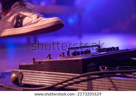 The guitarist kicks the switch on the effects processor during a concert performance.