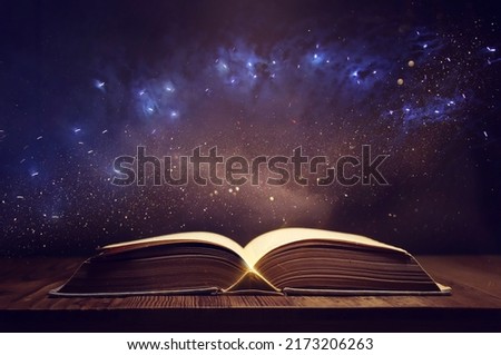 image of open antique book on wooden table with glitter overlay Royalty-Free Stock Photo #2173206263