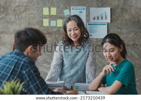 A startup executive is meeting with a new generation of employees to plan and discuss, she is an experienced senior executive with a modern mindset. Management concept of startup company.