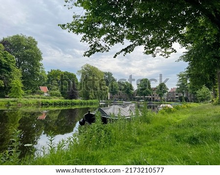 Beautiful view of city canal with moored boat surrounded by greenery