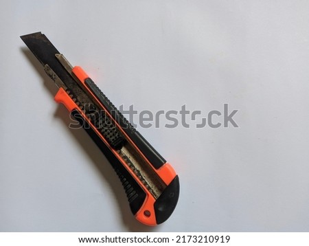 orange cutter knife on a plain white background