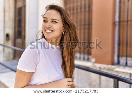 Attractive and beautiful hispanic woman smiling happy on a sunny day outdoors. Pretty brunette girl with positive smile looking confident at the city Royalty-Free Stock Photo #2173217983