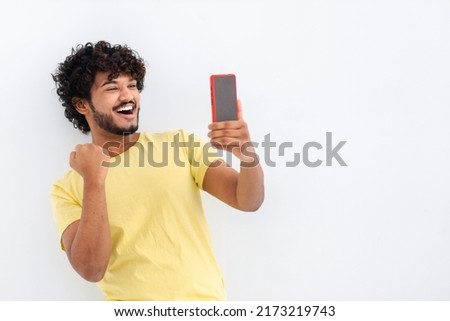 Excited surprised young Asian man holding mobile phone, got reading good news, notification about win. Male screaming yes, standing on a white background, he receive payment