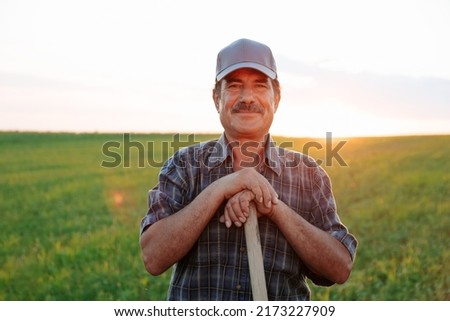 Old farmer with mustache handsome man looking at camera, male satisfied resting at sunset. the portrait of the worker in the agricultural field Royalty-Free Stock Photo #2173227909