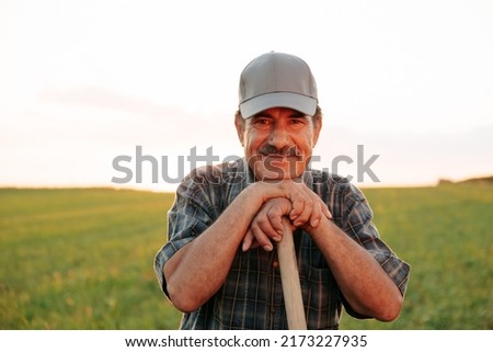 Old farmer with mustache handsome man looking at camera, male satisfied resting at sunset. the portrait of the worker in the agricultural field Royalty-Free Stock Photo #2173227935