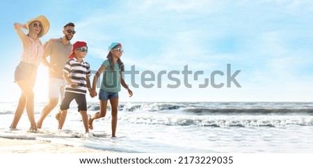 Happy family running on sandy beach near sea, space for text. Banner design