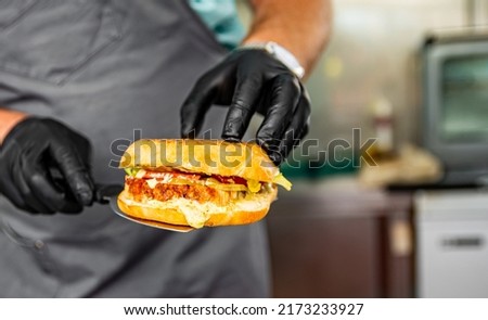 man chef hold on hand sandwich with cheese and sause on street food kitchen