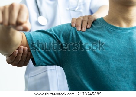 A man with shoulder pain goes to the doctor, The doctor diagnoses the patient's arm pain and shoulder pain. Concept of physical therapy and rehabilitation. Royalty-Free Stock Photo #2173245885