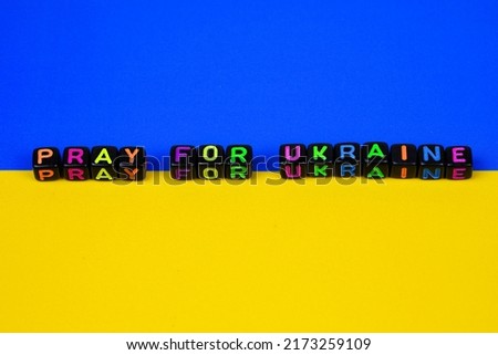 Multicolor word pray for Ukraine on Ukraine flag.