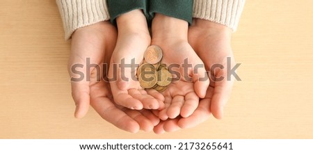 Hands of man and his son holding coins on wooden background. Concept of alimony Royalty-Free Stock Photo #2173265641