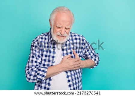 Picture of old pensioner grandfather touching chest suffering from heart attack isolated on teal color background