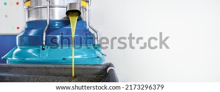 Process of producing fresh olive oil of first cold pressing at factory. Olive oil pours from tap of spin machine. Copy space, banner Royalty-Free Stock Photo #2173296379
