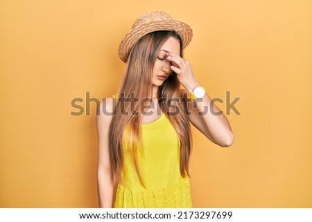 Young blonde girl wearing summer hat tired rubbing nose and eyes feeling fatigue and headache. stress and frustration concept. 