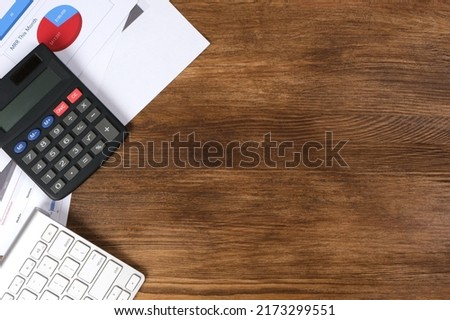 Top view of desktop with calculator keyboard and financial documents. Space for text on the right.