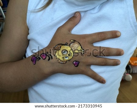child hand with print on white background.drawing of a dog with bronze paint