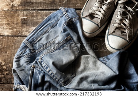 Pair of dirty jeans thrown on floor with a pair of sneakers