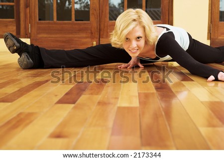 A Female Dancer practicing in her studio - in a split, on the floor