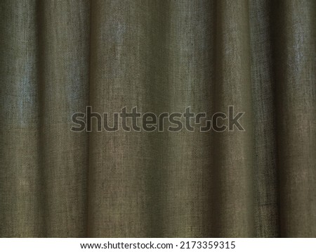 photo of light shining through blinds underneath a green curtain