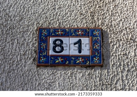 The number of the house is eighty-one 81 on the facade of the building on the street. Beautiful room on a legal basis. Blue border and white background.