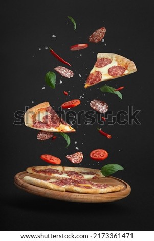 flying pizza with ingredients on a black background