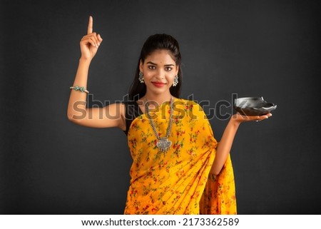 Young girl holding and posing with kitchen utensils on a grey background