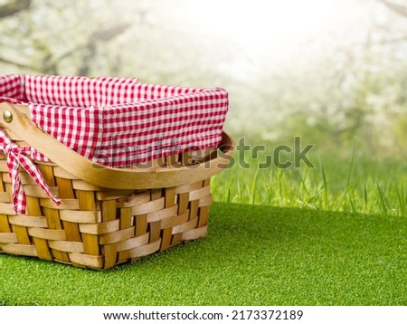 Cute straw picnic basket on green grass against the backdrop of picturesque summer nature. Rest, relaxation, day off. There are no people in the photo. There is free space to insert.