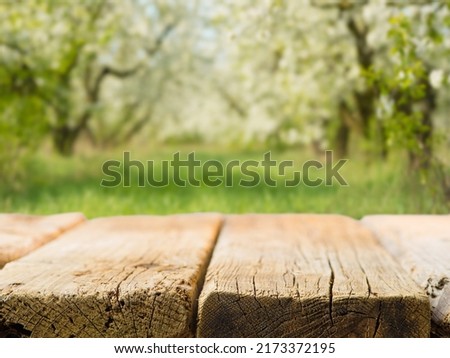 Wooden table on the background of picturesque nature. Green grass, flowering trees. Outdoor recreation, healthy lifestyle, beauty of nature, picnic, family vacation, romance.