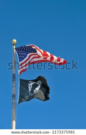 American and Pow Mia Flags waving against a blue sky