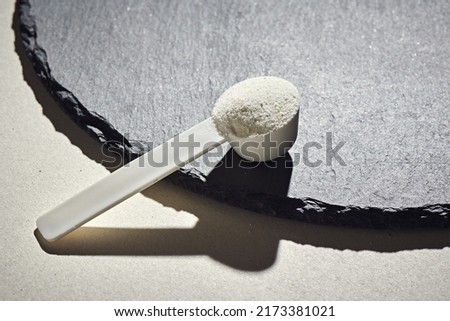 Sport food supplement powder with natural beige background and props. Supplement, creatine, hmb, bcaa, amino acid or vitamine in a white scoop. Sport nutrition concept... Check my profile for more! Royalty-Free Stock Photo #2173381021