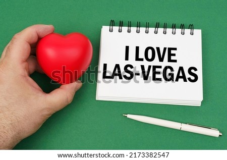 On the green surface are a pen, a notepad with the inscription - I love Las Vegas. A man has a heart in his hands.