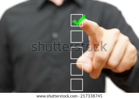 Young businessman checking mark on checklist with marker.
