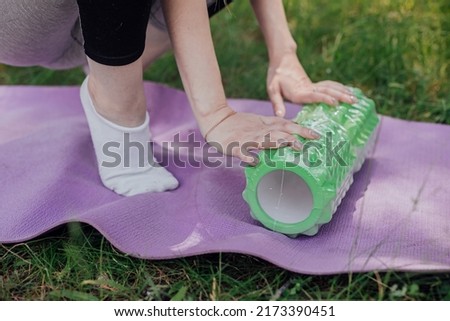 Woman practicing yoga and meditating outdoors. Girl preparing material for practice class in garden. Female happiness and yoga concept. During the quarantine due to the spread of the coronavirus