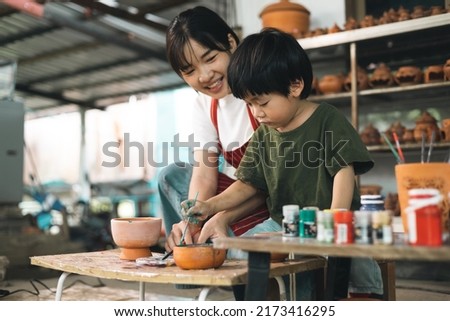 Happy family moment Mother teaching son how to painting mug cup ceramic workshop. Child creative activities and art. Kid playing  pottery workshop. Developing children's learning skills.