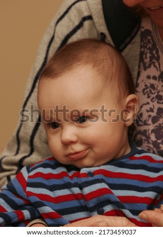 Close up picture of a cute brown hair baby boy smirking in a very mischievous way.