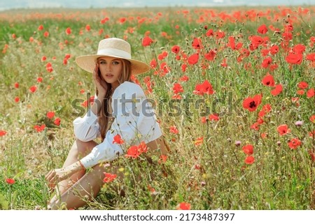 Young beautiful blonde woman with long hair in a poppy field