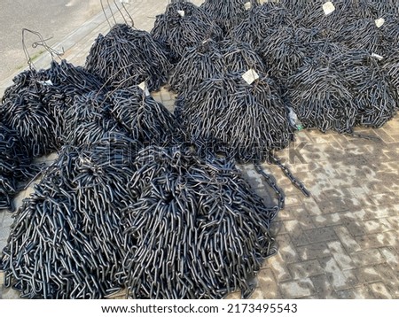 Round link chains for conveying and elevating equipment are folded in a heaps. A lot of steel chains stacks Royalty-Free Stock Photo #2173495543