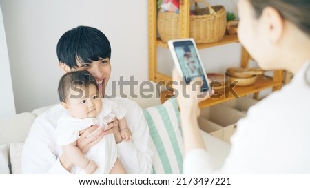 Asian couple shooting photo of their baby with a smart phone.