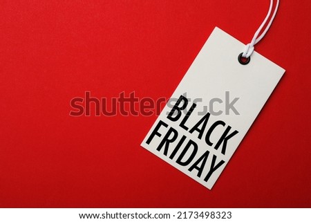 White tag with phrase BLACK FRIDAY on red background, top view. Space for text