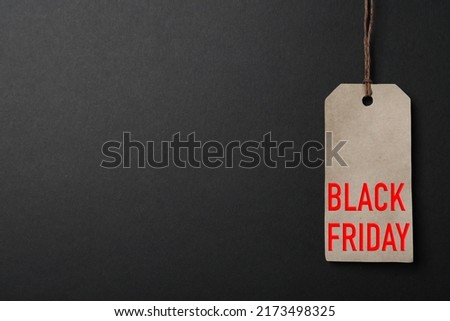 LIght grey tag with phrase BLACK FRIDAY on dark background, top view. Space for text