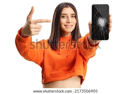 Young female pointing at a smartphone with broken screen isolated on white background