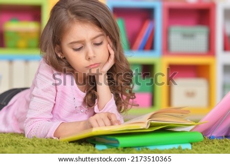 portrait of sad girl doing homework on the floor