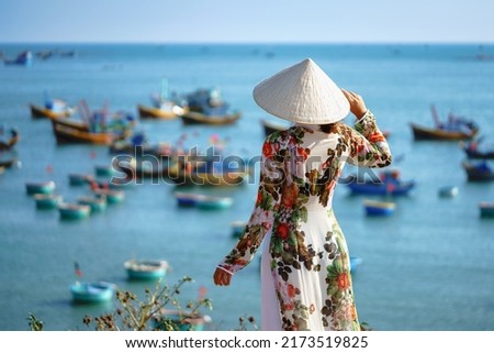 Vietnamese lady with Ao Dai Vietnam traditional dress and conical hat wait at the harbor, Fishing Harbour Mui Ne Vietnam Royalty-Free Stock Photo #2173519825