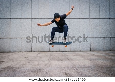 Asian woman skateboarder skateboarding in modern city Royalty-Free Stock Photo #2173521455