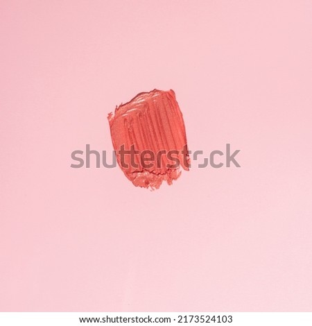 Swatch of pink shimerry lipstick on pink background